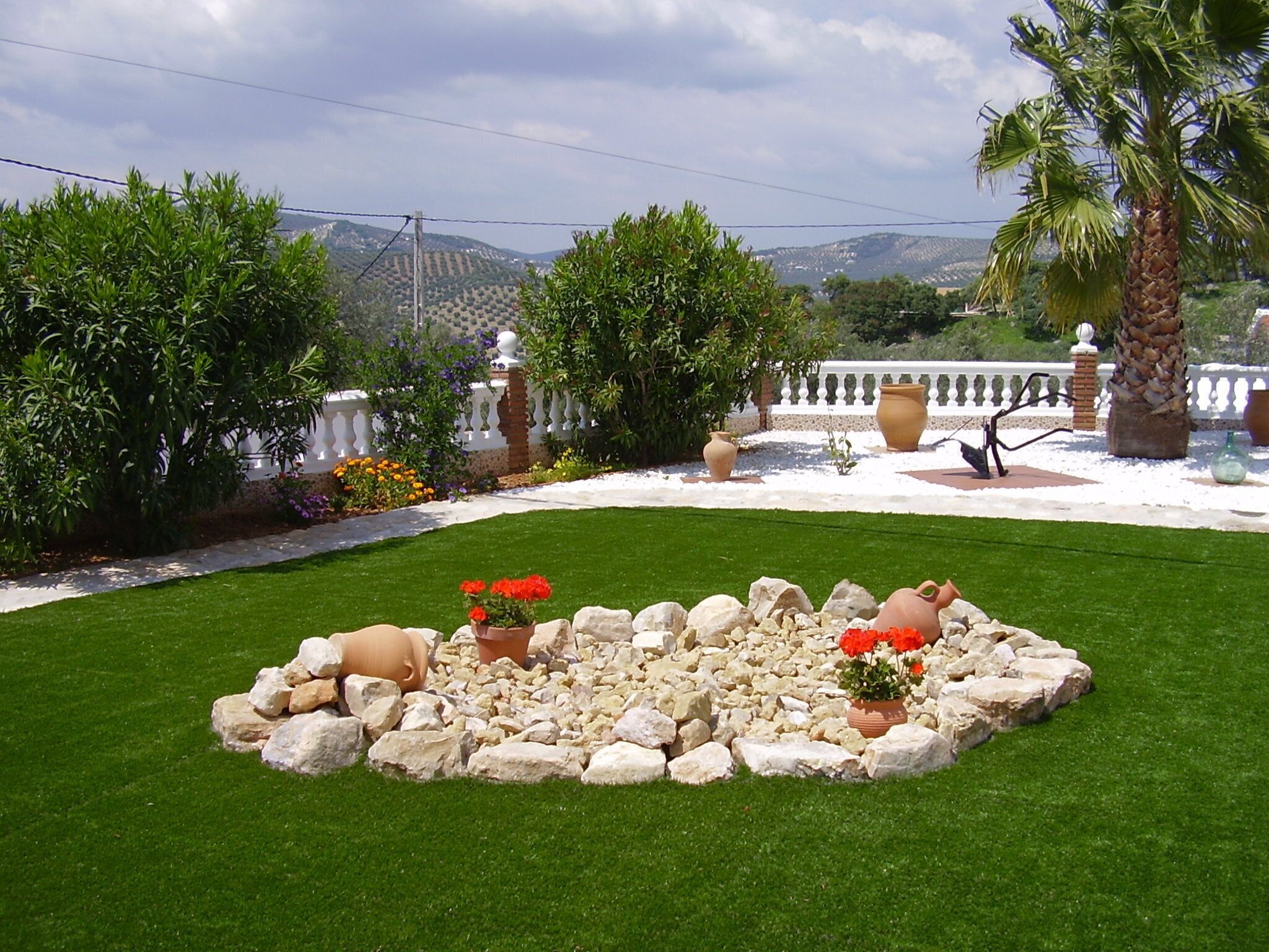 A landscaped garden with a rock border, potted plants, and a palm tree.