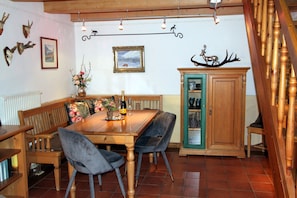 A dining area with a wooden table, chairs, a cabinet, and wall-mounted deer antlers.