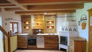 A compact kitchen with wooden cabinets, a dishwasher, a stove, and a sink. - "schossbach" Baubiologische Ferienwohnung 60 qm, Zwei Extra Schlafzimmer (Aschau im Chiemgau)