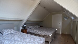 A bedroom with two beds, wooden flooring, and a sloped ceiling. - holiday home for 10 people (Oostvleteren)