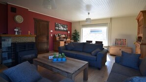 A cozy living room with a fireplace, a sofa set, a coffee table with potted plants, and a wooden cabinet. - holiday home for 10 people (Oostvleteren)