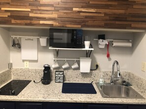 A kitchen with a granite countertop, a coffee maker, a microwave, a sink, and a wooden backsplash. - Casa Indigo -- Cozy & Chic in GREAT LOCATION! (San Antonio)