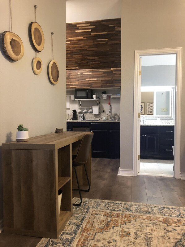 A modern kitchen with a wooden island, dark cabinets, and a patterned rug. - Casa Indigo -- Cozy & Chic in GREAT LOCATION! (San Antonio)