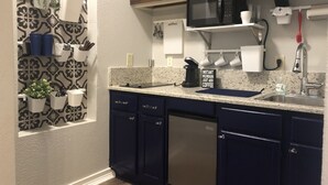 A kitchen with dark blue cabinets, a stainless steel sink, a microwave, and a coffee maker. - Casa Indigo -- Cozy & Chic in GREAT LOCATION! (San Antonio)