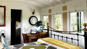 Une chambre à coucher avec un lit, un bureau, une chaise, une horloge et une fenêtre.