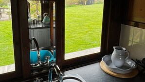 Une cuisine avec un évier bleu, un panneau d’avertissement concernant la fumée, et une vue sur une pelouse verdoyante par la fenêtre.
