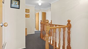 Ein Flur mit einer Holztreppe, einer Tür mit einem runden Knauf und gerahmten Bildern an der Wand.