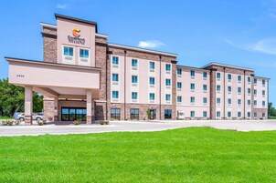 Un hotel de varios pisos con techo plano, entrada central y césped bien cuidado al frente.