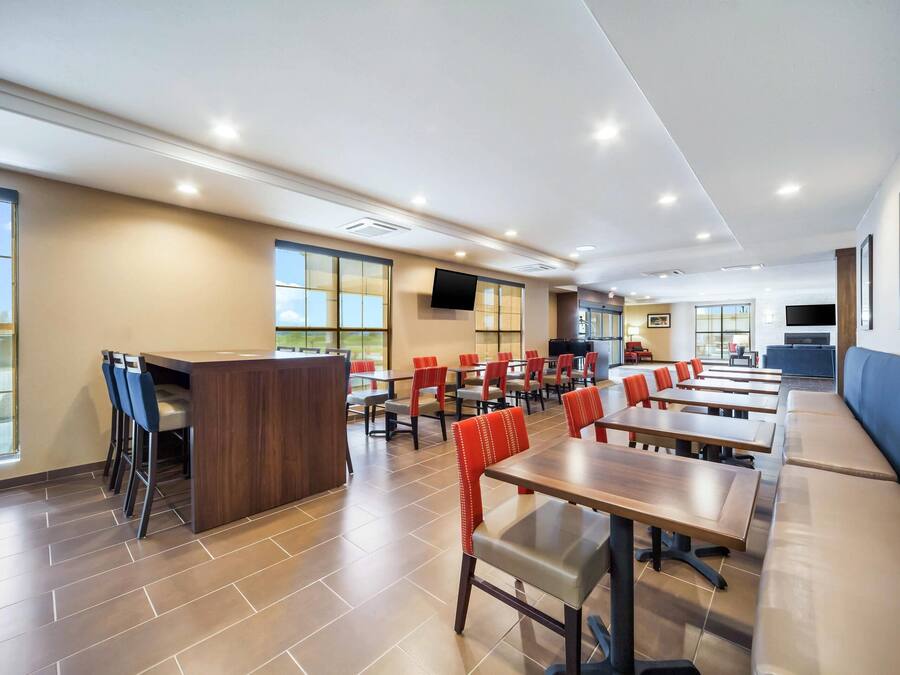 A modern dining area with multiple tables and chairs, a counter, and large windows providing natural light.