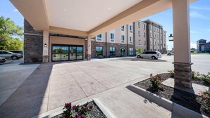A hotel entrance with a covered patio, stone pillars, and a parking lot.