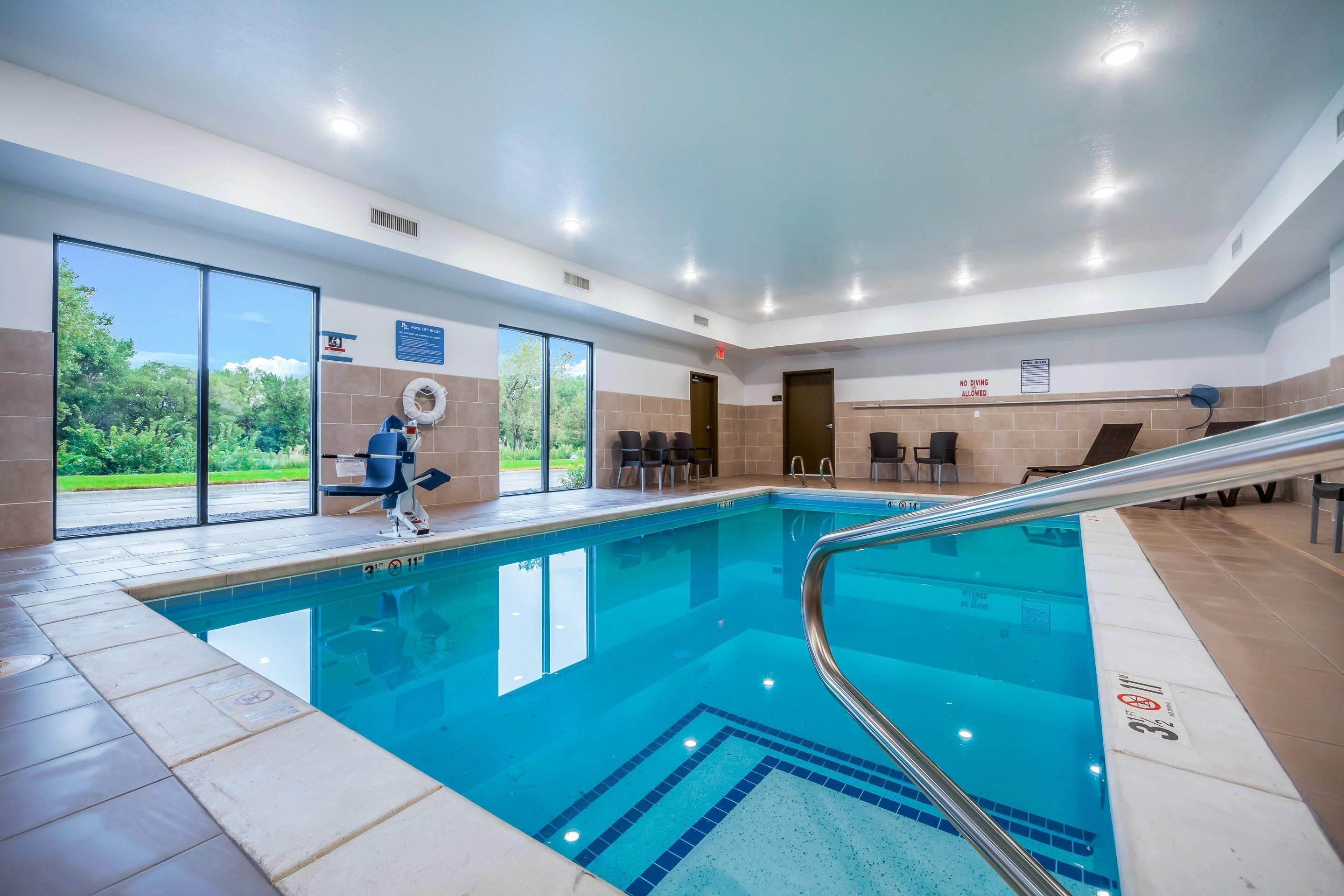 Una piscina interior con paredes de vidrio transparente, una silla de salvavidas y un letrero que prohíbe el clavado.
