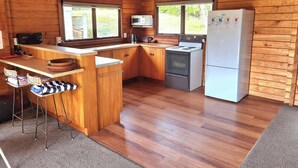 Una cucina compatta con pareti in legno, un'isola centrale, sgabelli da bar e un frigorifero.