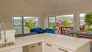 A modern kitchen with a built-in dishwasher, large windows, and a dining area with a table set for four.