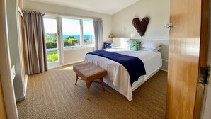 A bedroom with a large bed, a view of the outdoors, and a heart-shaped decoration on the wall.