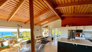 A spacious kitchen with a large island, a dining area with a view of the ocean, and a cozy seating area with a view of the beach.