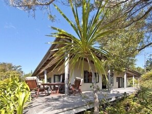 A house with a patio area, outdoor furniture, and a large tree in the foreground.