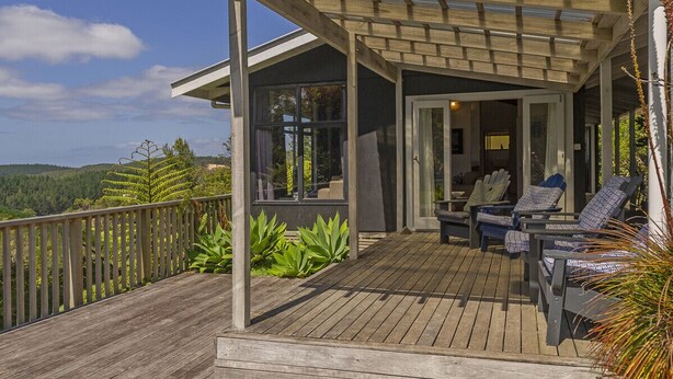 A wooden deck with outdoor seating and a covered area. - Hahei Hideaway - Hahei Holiday Home (Hahei)