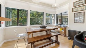 A spacious room with large windows, a wooden table, a bench, and a radiator.