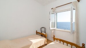 Ein Zimmer mit zwei Betten, einem Vorhangfenster und Meerblick.