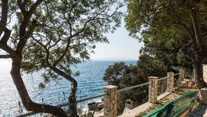 Eine Küstenbank mit Blick auf das Meer, mit Steinzaun und Grünpflanzen.