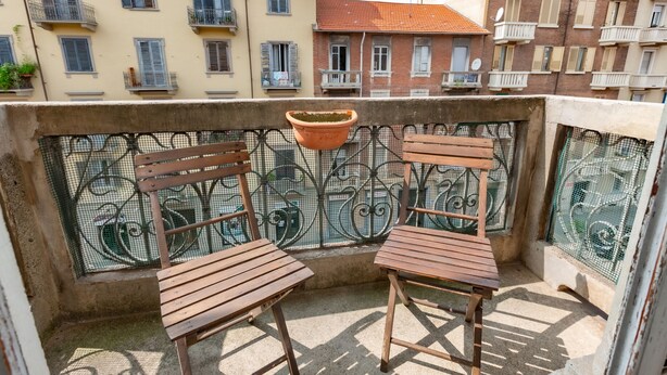 A balcony with two wooden chairs and a hanging basket. - Grotta di Rita (Turin)