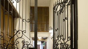 Um corredor estreito com portões de metal preto ricamente decorados na entrada.
