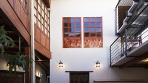 Um edifício com fachada branca, varandas de madeira e plantas penduradas.