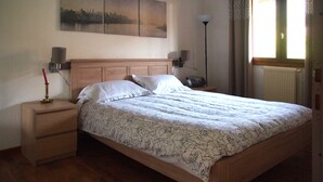 Et soveværelse med en træseng, et natbord, en lampe og et maleri på væggen.
