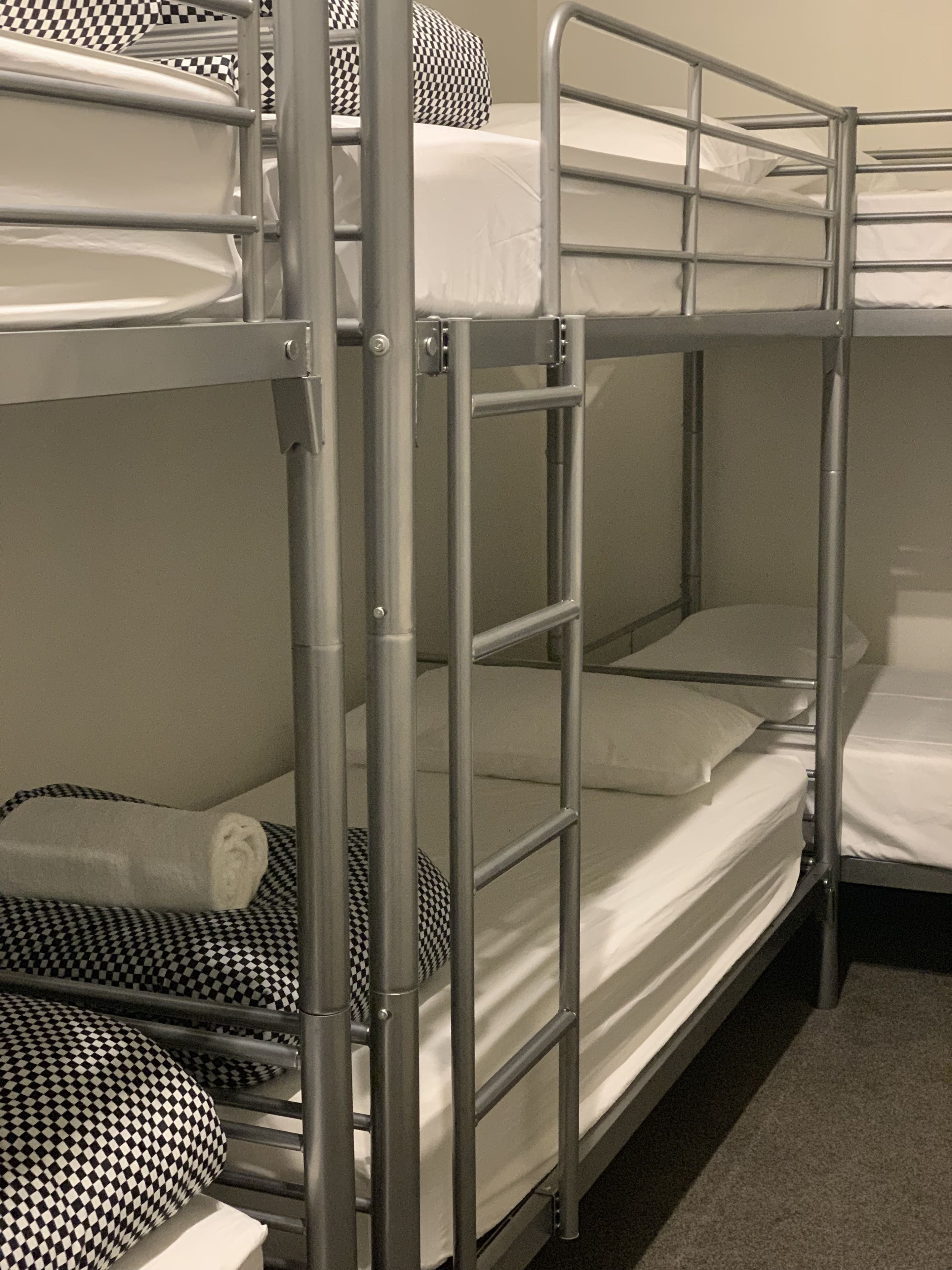 A bunk bed with metal railings and checkered bedding.