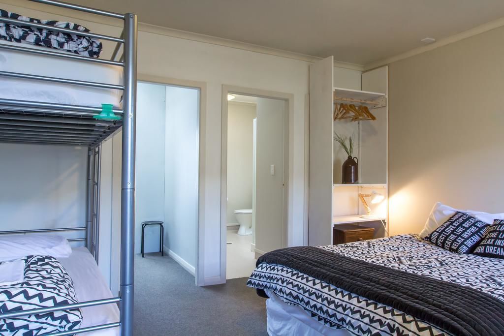 Une chambre avec des lits superposés, une table de chevet avec une lampe et une armoire.