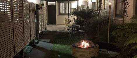 A backyard with a fire pit, a covered patio, and a fenced area.
