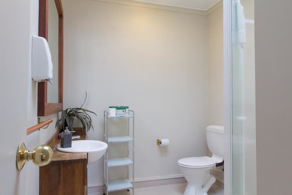 Ein kleines Badezimmer mit einem weißen Waschbecken, einer Toilette und einer kleinen Ablagefläche.