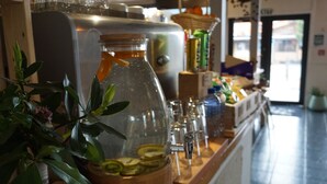 A bar area with a glass jar filled with sliced fruits, a stainless steel appliance, and various bottles and glasses. - Snowman Lodge (Ohakune)