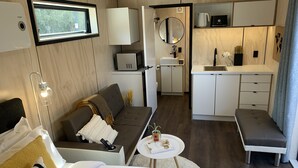 A modern hotel room with a sofa, a small table, a bed, a kitchenette, and a bathroom. - Snowman Lodge (Ohakune)