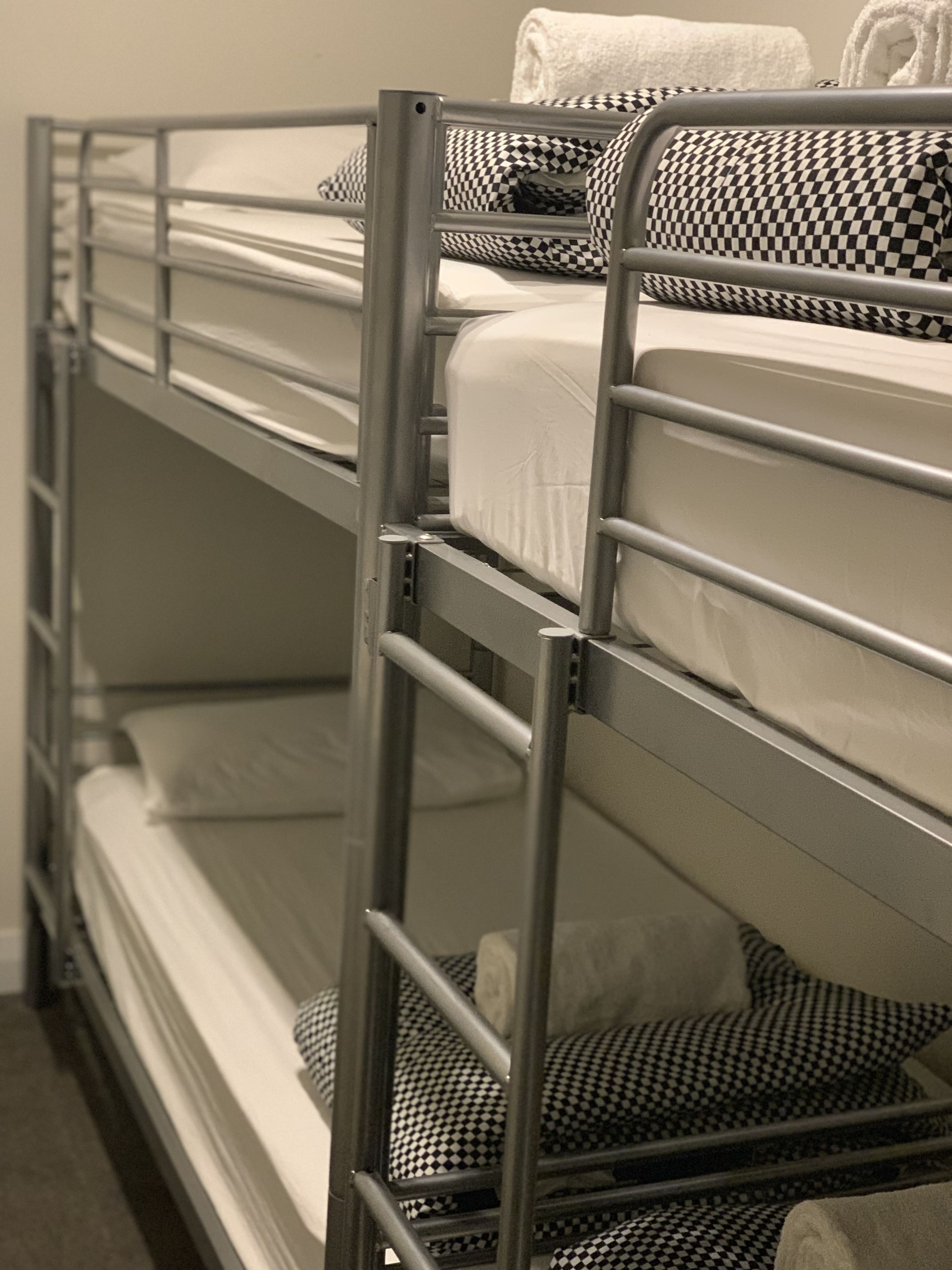 Un lit superposé avec des barreaux en métal et une literie à carreaux.