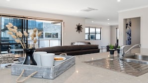 Una sala de estar moderna con un sofá, una mesa de centro con objetos decorativos, y una zona de cocina con un fregadero y encimera.