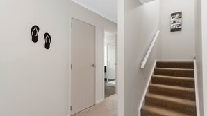 Un pasillo con alfombra, una escalera, una puerta y una obra de arte colgada en la pared.