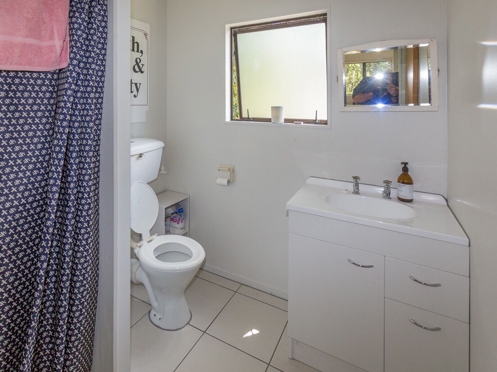 Een badkamer met toilet, wastafel en spiegel.