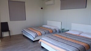 A hotel room with two beds, a chair, and a small table. - Pine Lake View Lodge (Kaiapoi)