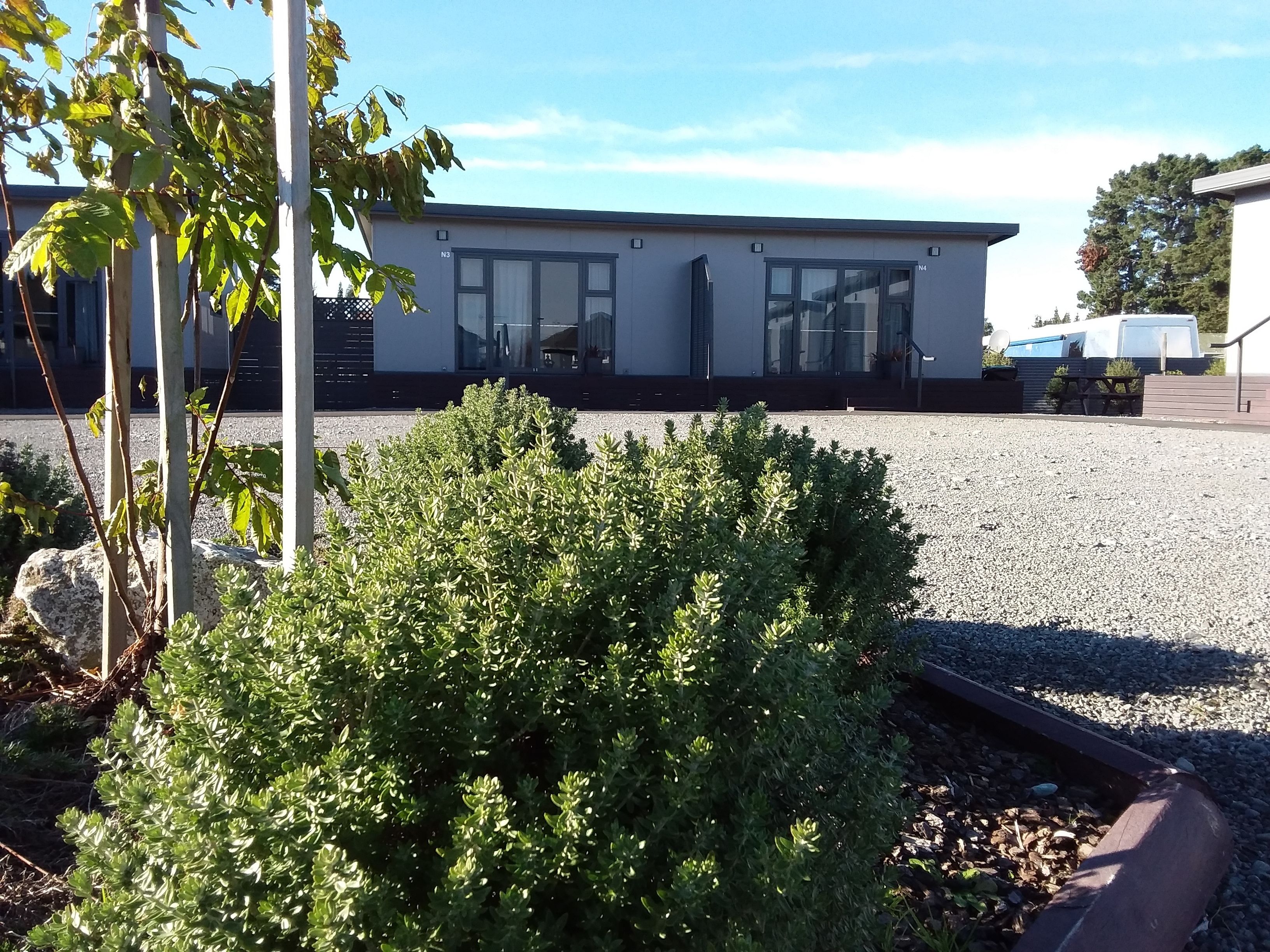 A modern building with large windows and a gravel driveway.