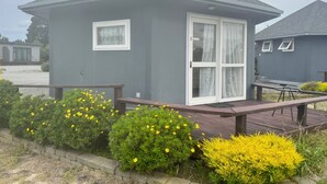 A small, single-story building with a gray exterior and a white-framed door. - Pine Lake View Lodge (Kaiapoi)