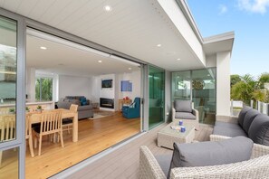 A modern living space with a wooden floor, a sofa, a dining table, and a fireplace. - Modern Muricata - Enjoy Beach, Surf & Sun (Omanu)