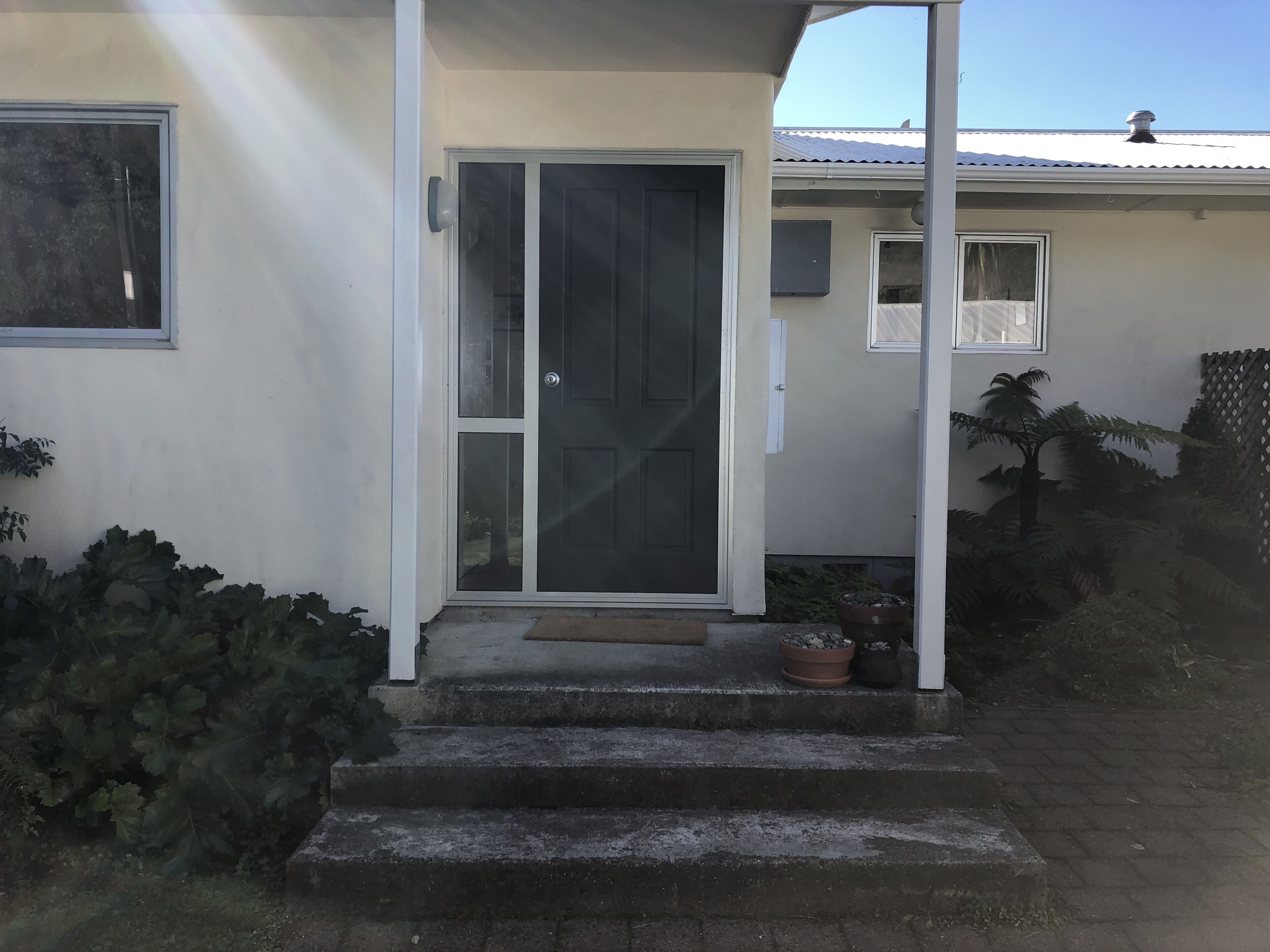 Une maison avec une porte d’entrée, un petit porche et des marches menant à l’entrée.