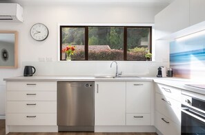 A modern kitchen with a dishwasher, sink, and oven. - The Nest in The Wood - peaceful & private, and walking distance to Nelson City (Nelson City)
