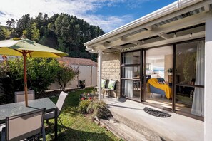 A modern house with a patio, a dining table, and a yellow umbrella. - The Nest in The Wood - peaceful & private, and walking distance to Nelson City (Nelson City)