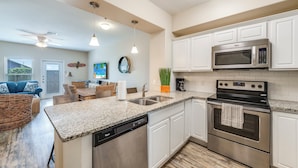 A modern kitchen with white cabinets, stainless steel appliances, and a granite countertop. - Family Getaway | Heated Pool, Playground & Beach Close By (Corpus Christi)