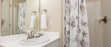 A bathroom with a white sink, a mirror, and a shower curtain with a sea creature pattern.