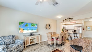 A living room with a television, wicker furniture, a dining area, and a kitchen. - Family Getaway | Heated Pool, Playground & Beach Close By (Corpus Christi)