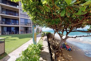 Un hotel con piscina, vista al mar y un paseo bordeado de árboles.
