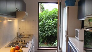 A compact kitchen with a sink, stove, and a bowl of fruit on the counter. - Spacious,  quiet family flat with terrace and parking in the 18th Montmatre (Paris)
